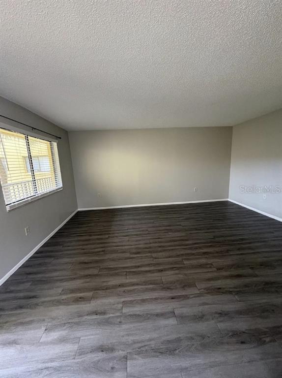 An empty room with gray walls, dark wood-look flooring, and a window with blinds — 2683 OAK PARK WAY UNIT 214, ORLANDO, FL