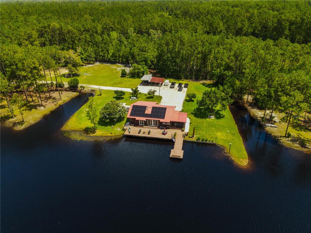 An aerial view shows a house with solar panels on a lakefront lot — 153897 COUNTY ROAD 108, YULEE, FL