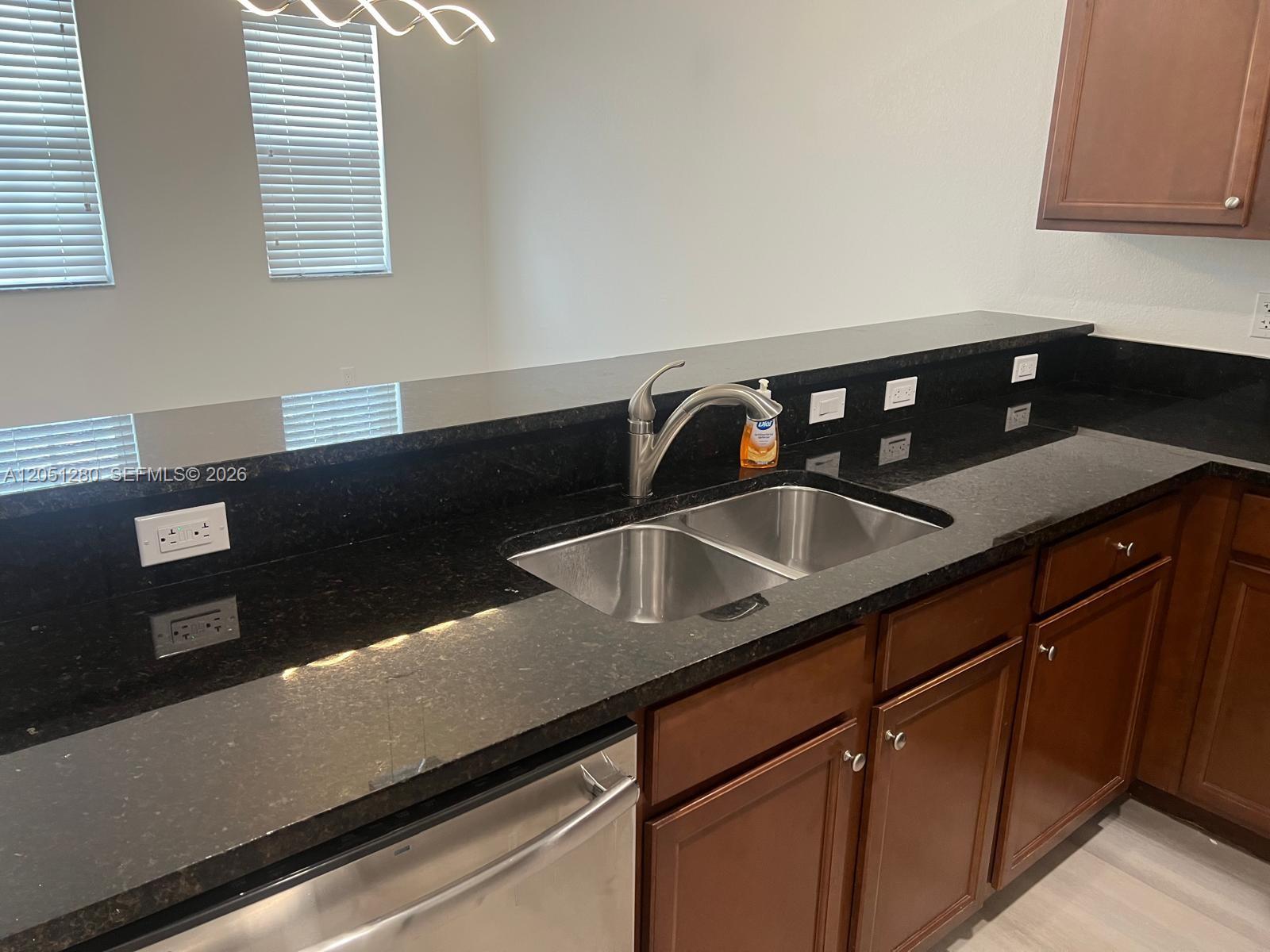 A kitchen features dark granite countertops, a stainless steel double sink, and brown wooden cabinets — 8760 NW 97th Ave # 205, Doral FL 33178, DORAL, FL