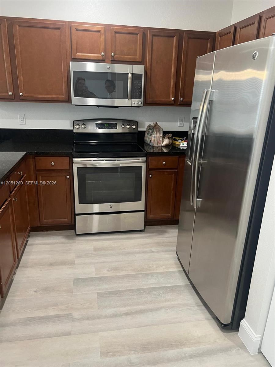 A kitchen features stainless steel appliances, dark wood cabinets, and light-colored wood-look flooring — 8760 NW 97th Ave # 205, Doral FL 33178, DORAL, FL