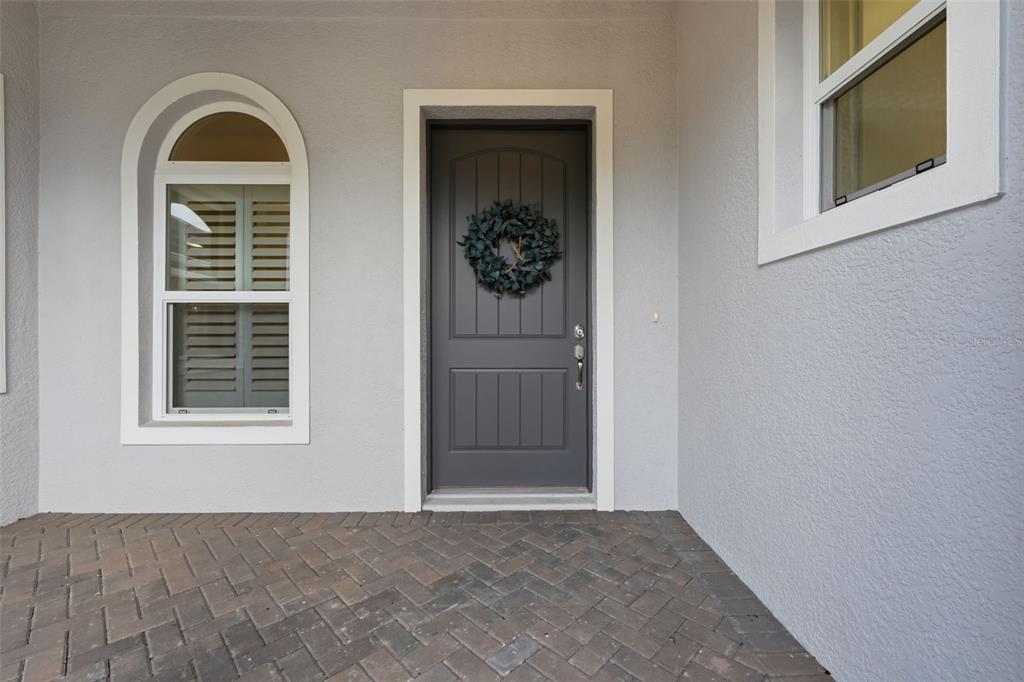 A gray front door with a wreath sits beside an arched window on a porch — 5066 GREENS DRIVE, LADY LAKE, FL