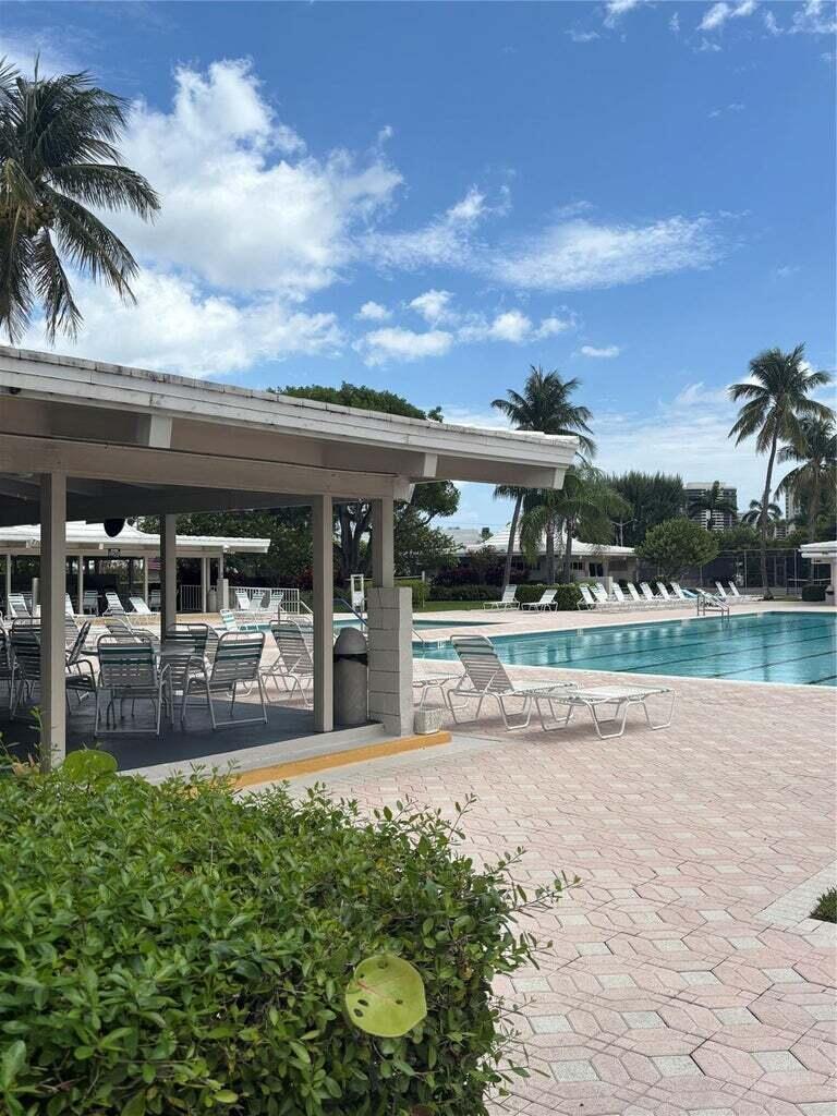 A covered patio with outdoor seating overlooks a swimming pool surrounded by lounge chairs — 1260 Sugar Sands Boulevard # 206, Singer Island FL 33404, SINGER ISLAND, FL