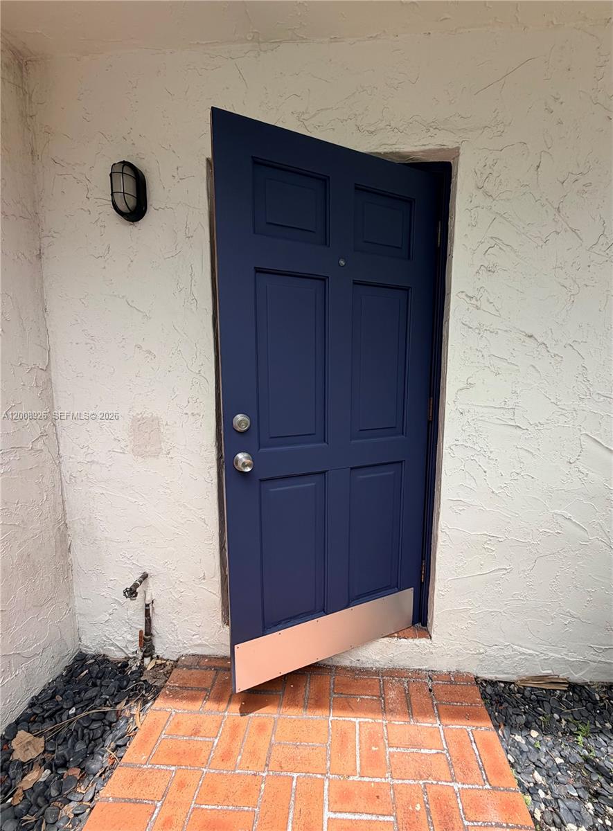 A dark blue six-panel door with a kick plate stands open against a textured wall — 3225 Bird Ave, Miami FL 33133, MIAMI, FL