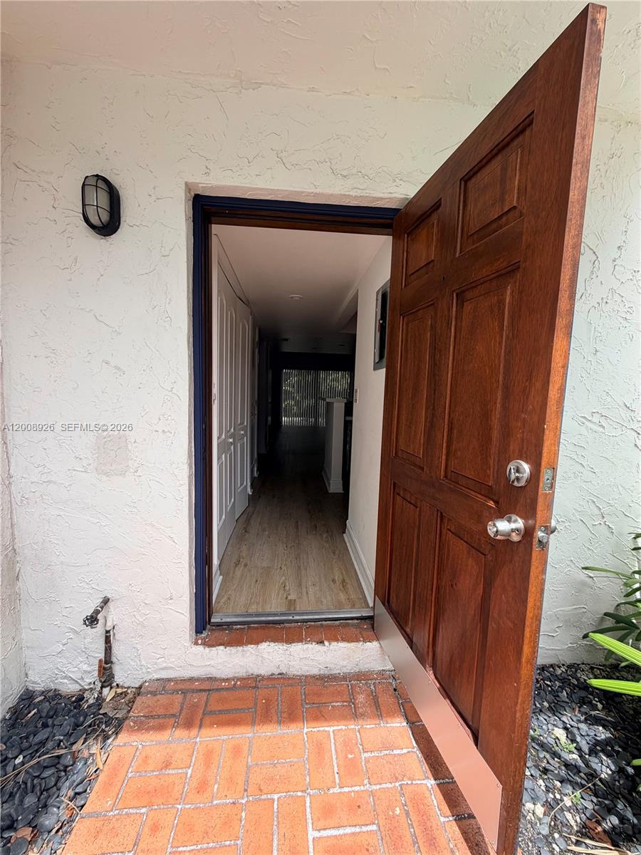 An open wooden door reveals a hallway with light wood flooring and white walls — 3225 Bird Ave, Miami FL 33133, MIAMI, FL