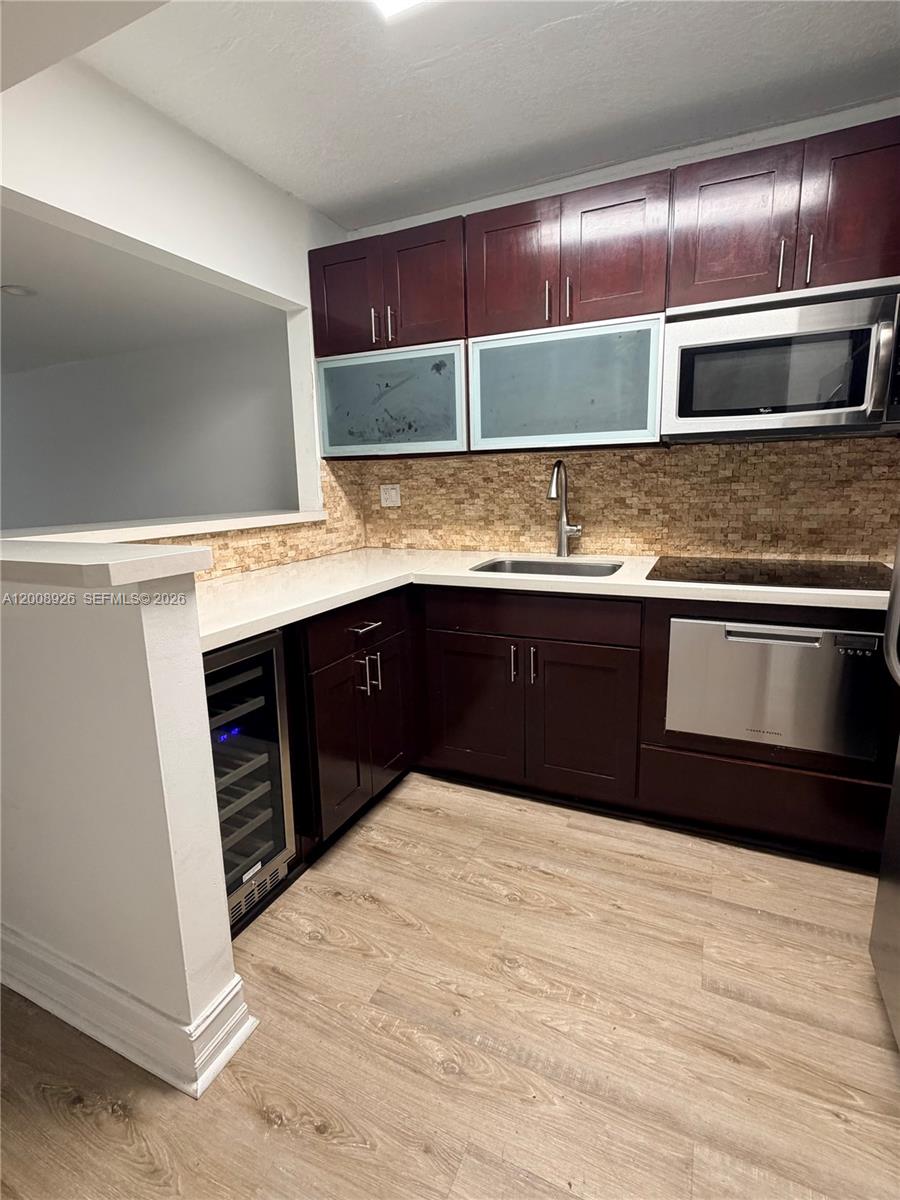 A kitchen features dark wood cabinets, stainless steel appliances, a wine cooler, and stone backsplash — 3225 Bird Ave, Miami FL 33133, MIAMI, FL