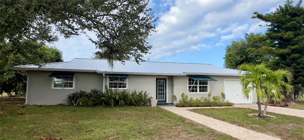 A single-story house with a metal roof, light-colored exterior, and a front walkway — 4501 ROYAL PALM RANCH DRIVE, ST JAMES CITY, FL