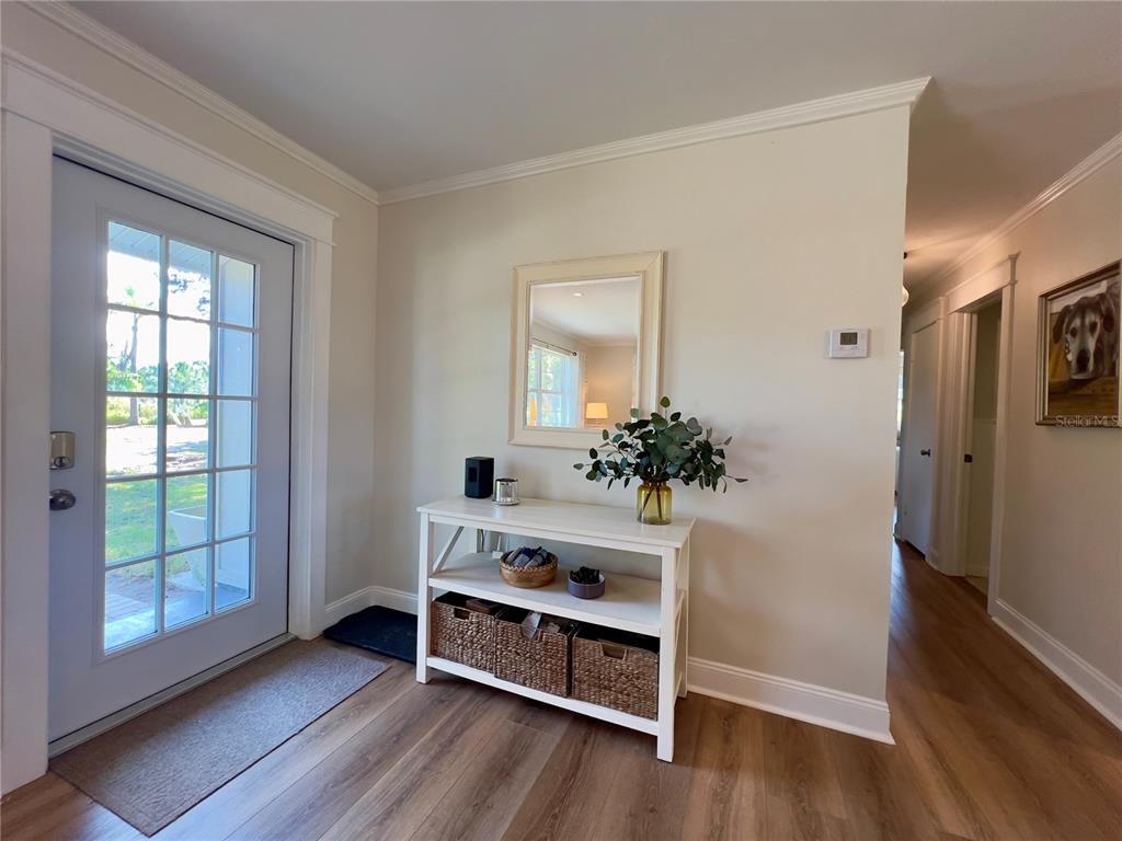 An entryway features a white console table, a wall mirror, and wood-look flooring — 4501 ROYAL PALM RANCH DRIVE, ST JAMES CITY, FL
