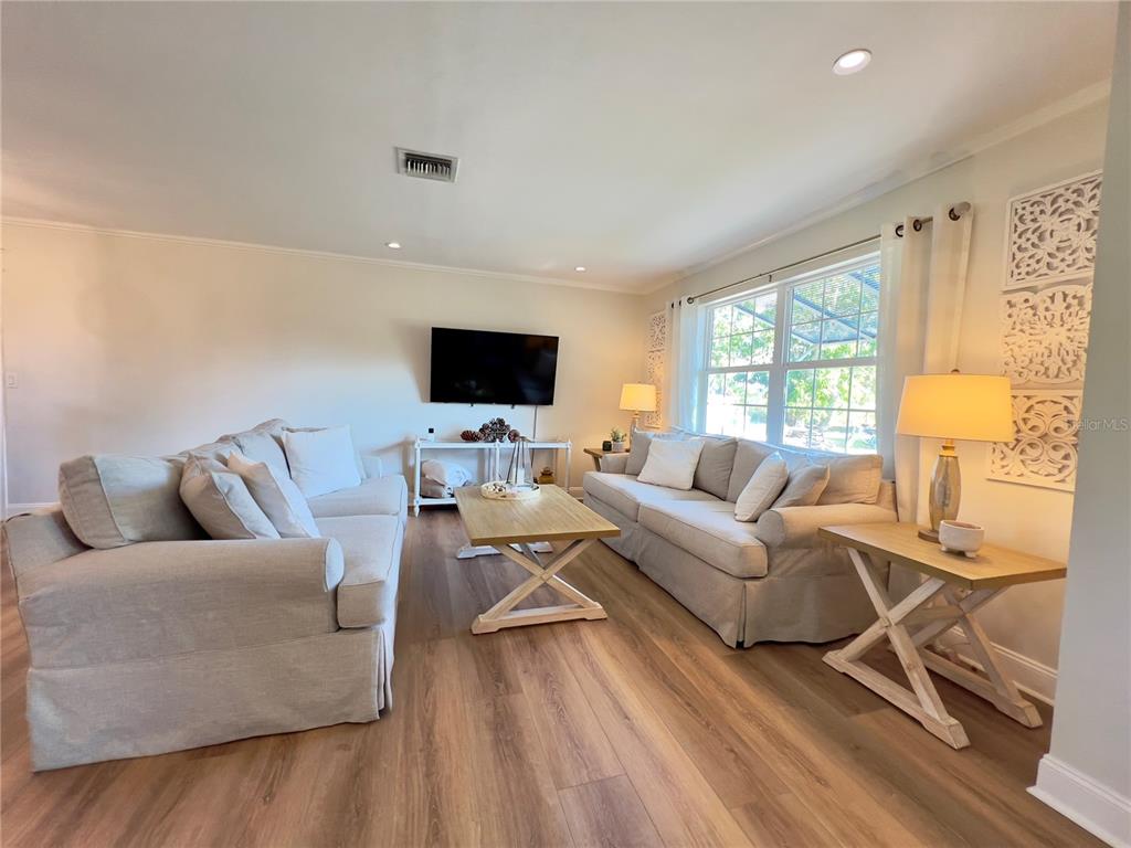 A living room features two light-colored sofas, a wooden coffee table, and wood-look flooring — 4501 ROYAL PALM RANCH DRIVE, ST JAMES CITY, FL