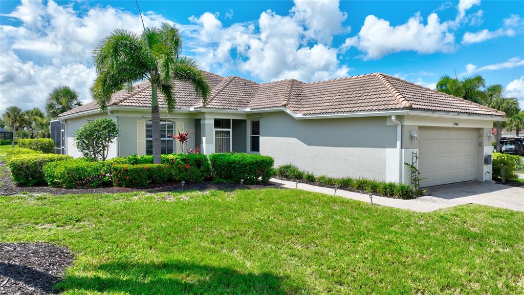 A single-story house with a beige exterior, a tiled roof, and a two-car garage — 17900 COURTSIDE LANDINGS CIRCLE, PUNTA GORDA, FL