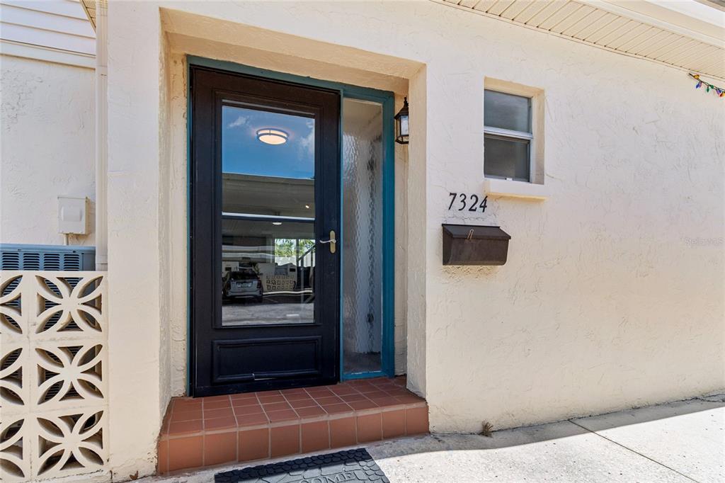 A black front door with a glass sidelight sits next to a house number and mailbox — 7324 STONE HAVEN COURT N, PINELLAS PARK, FL