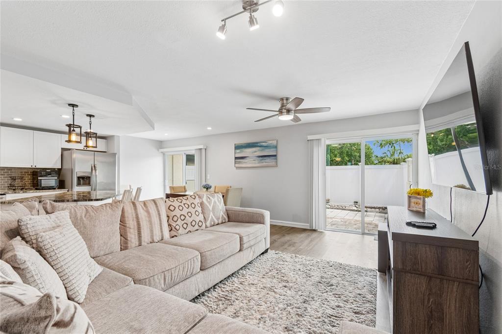 A living room with a sectional sofa, ceiling fan, and sliding doors to a patio — 7324 STONE HAVEN COURT N, PINELLAS PARK, FL