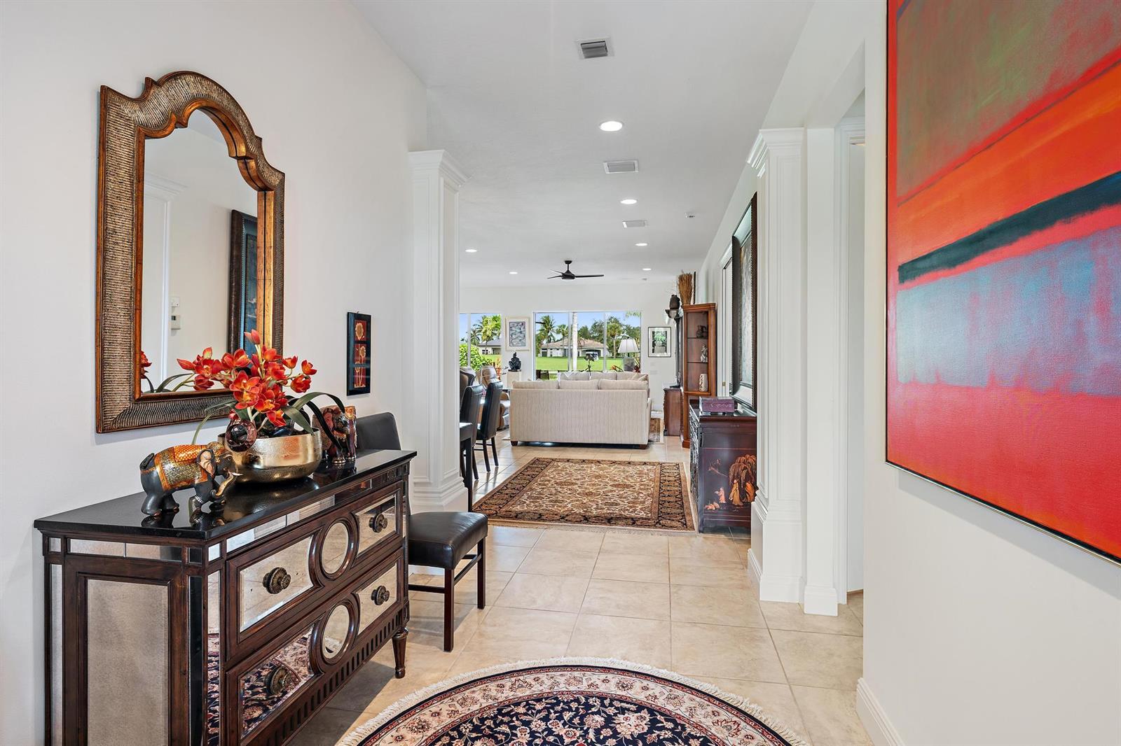A foyer with a mirrored chest and mirror leads into a living room with tile floors — 10675 La Strada, West Palm Beach FL 33412, WEST PALM BEACH, FL