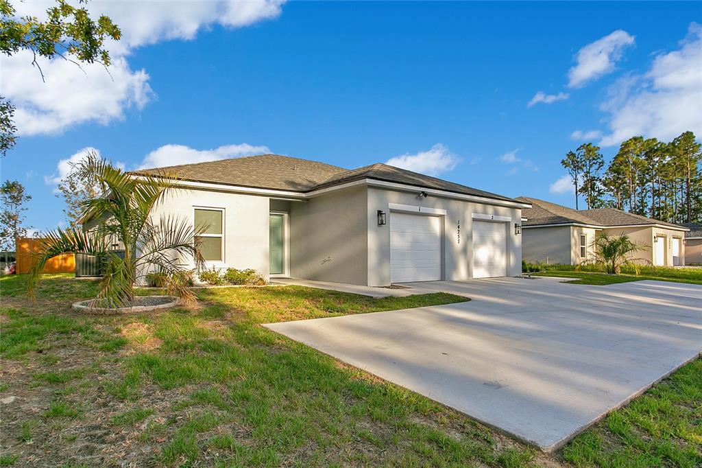 A single-story house with a light-colored stucco exterior and a two-car garage — 14257 SW 60TH TERRACE UNIT 1, OCALA, FL