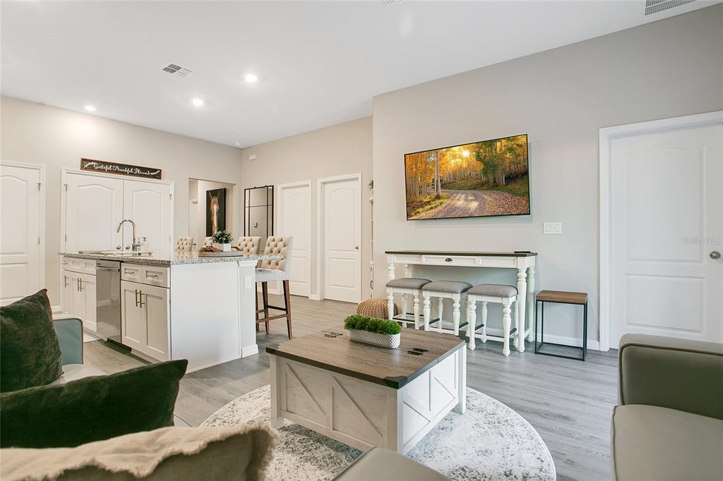 A modern open-concept living room and kitchen featuring a white island and gray flooring — 14257 SW 60TH TERRACE UNIT 1, OCALA, FL