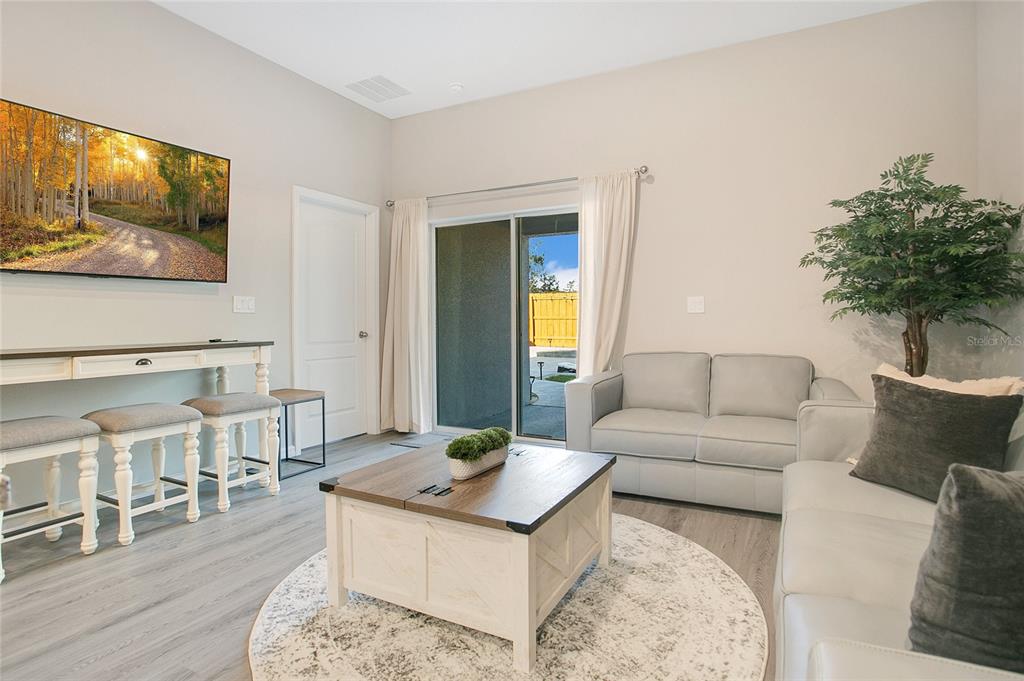 A living room features a white coffee table, light gray sofas, and a sliding glass door — 14257 SW 60TH TERRACE UNIT 1, OCALA, FL