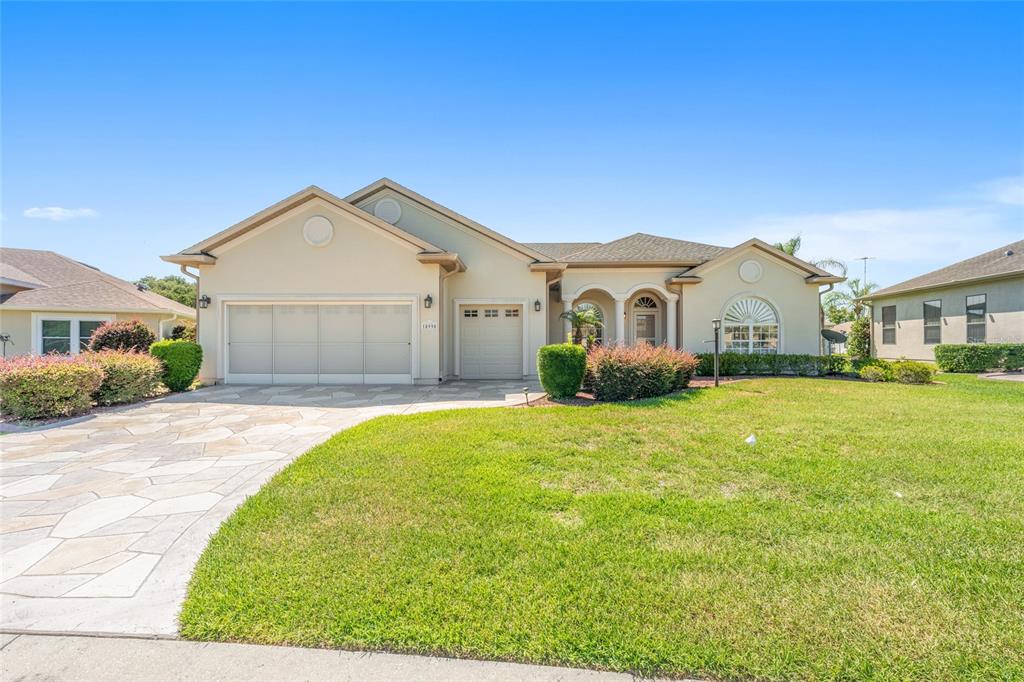 A single-story house with a beige stucco exterior, a stone driveway, and a three-car garage — 10990 SE 170TH STREET ROAD, SUMMERFIELD, FL