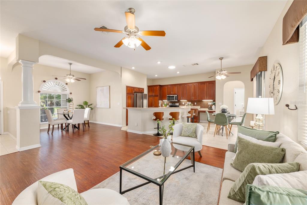 An open-concept living area features a kitchen with wood cabinets, dining spaces, and hardwood floors — 10990 SE 170TH STREET ROAD, SUMMERFIELD, FL