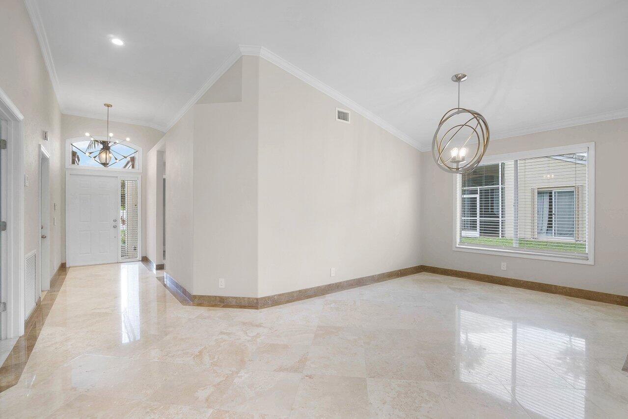 An empty room with light-colored tile floors, a modern chandelier, and a large window — 660 NW 45th Avenue, Deerfield Beach FL 33442, DEERFIELD BEACH, FL