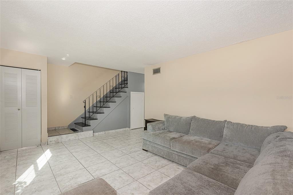 A living room features light tile flooring, a gray sectional sofa, and a staircase — 3686 SW 59TH TERRACE UNIT 71, FORT LAUDERDALE, FL