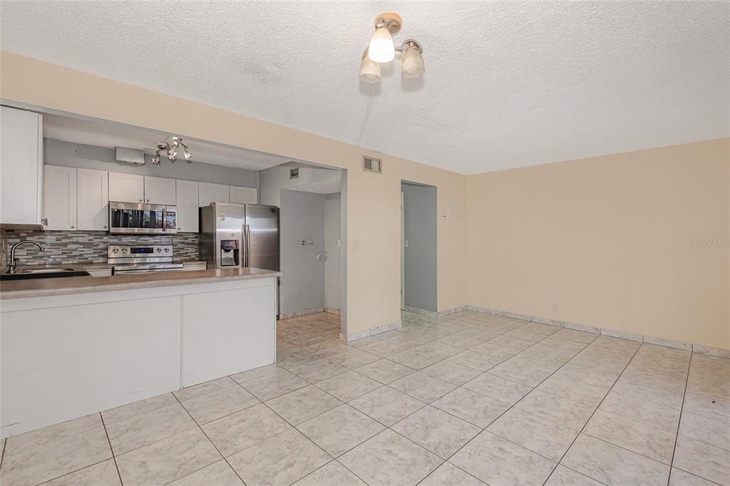 An open-concept kitchen and dining area features white cabinets, stainless steel appliances, and tile flooring — 3686 SW 59TH TERRACE UNIT 71, FORT LAUDERDALE, FL