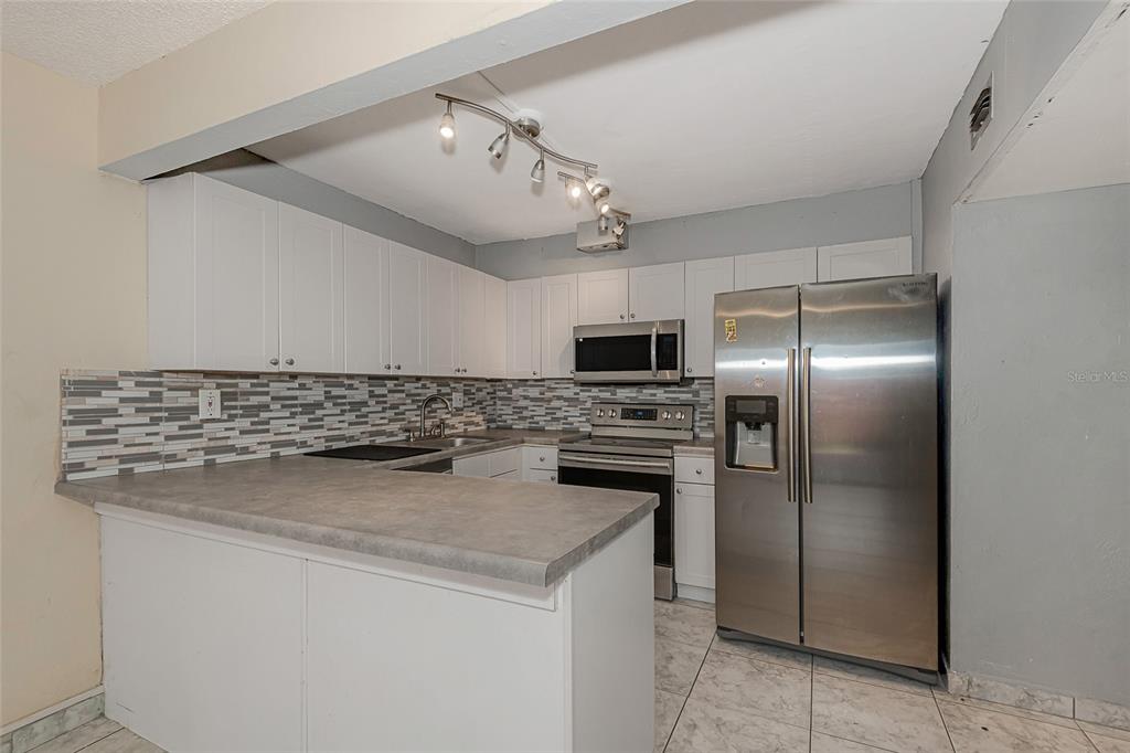 A kitchen features white cabinets, gray countertops, stainless steel appliances, and a tiled backsplash — 3686 SW 59TH TERRACE UNIT 71, FORT LAUDERDALE, FL