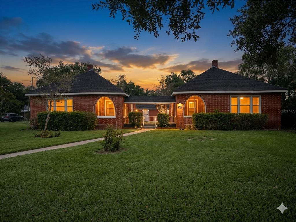 A brick house with two wings connected by a covered walkway under a sunset sky — 425 E SESSOMS AVENUE, LAKE WALES, FL
