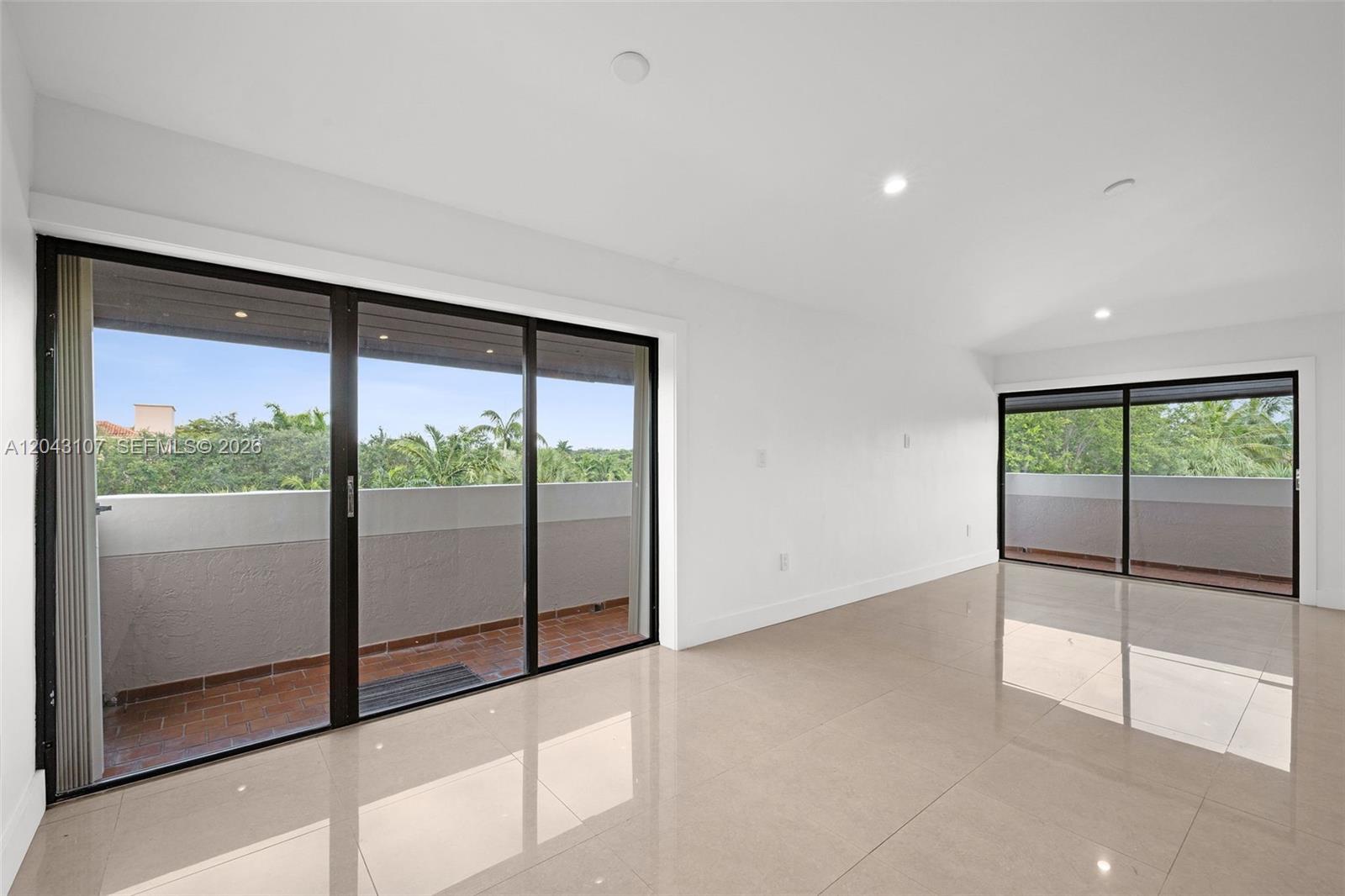 A bright room features light tile flooring, white walls, and two sliding glass balcony doors — 9001 SW 94th St # 201, Miami FL 33176, MIAMI, FL