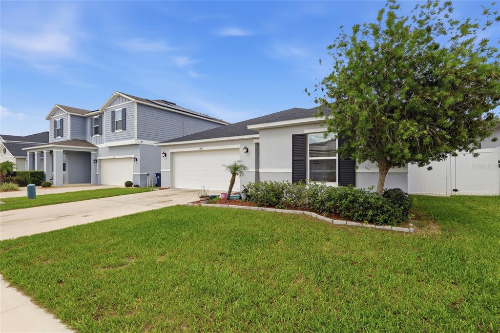 A single-story gray house with a two-car garage and a front yard with a tree — 1341 MATTIE POINTE BOULEVARD, AUBURNDALE, FL