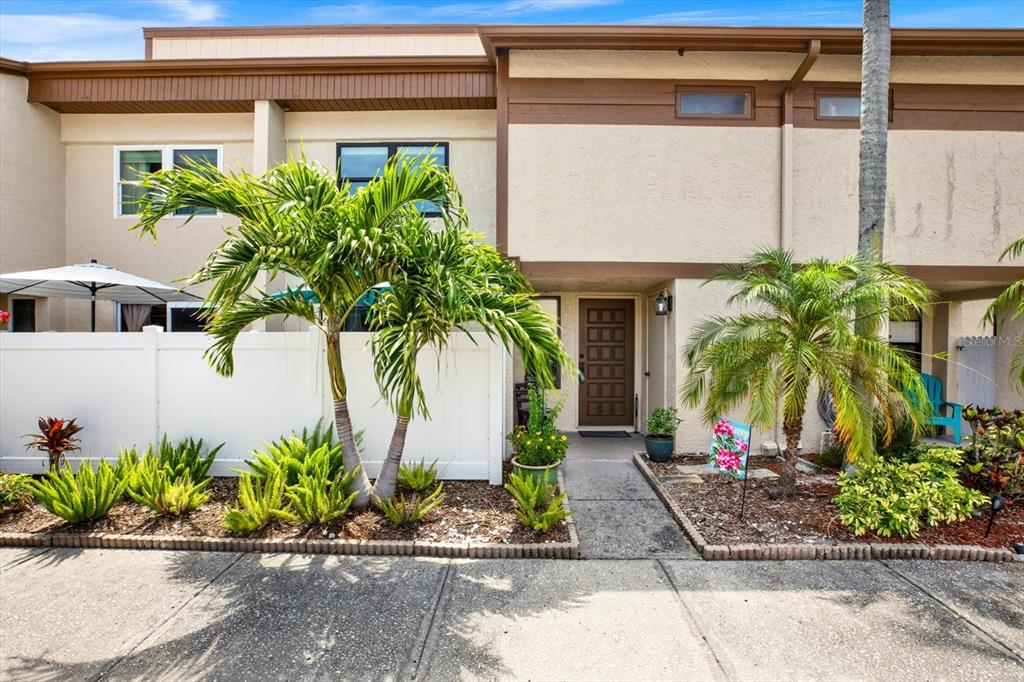 A two-story townhouse exterior features a brown front door, palm trees, and a white fence — 9209 SEMINOLE BOULEVARD UNIT 14, SEMINOLE, FL
