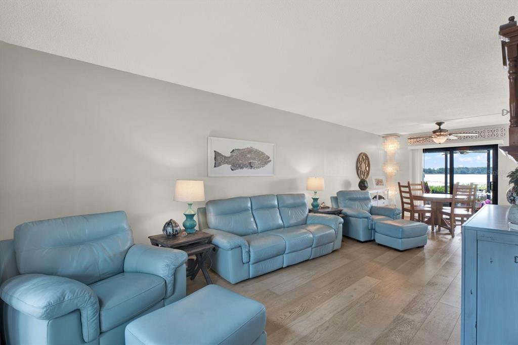 A living room features light blue leather furniture, wood-look flooring, and a view of water — 9209 SEMINOLE BOULEVARD UNIT 14, SEMINOLE, FL