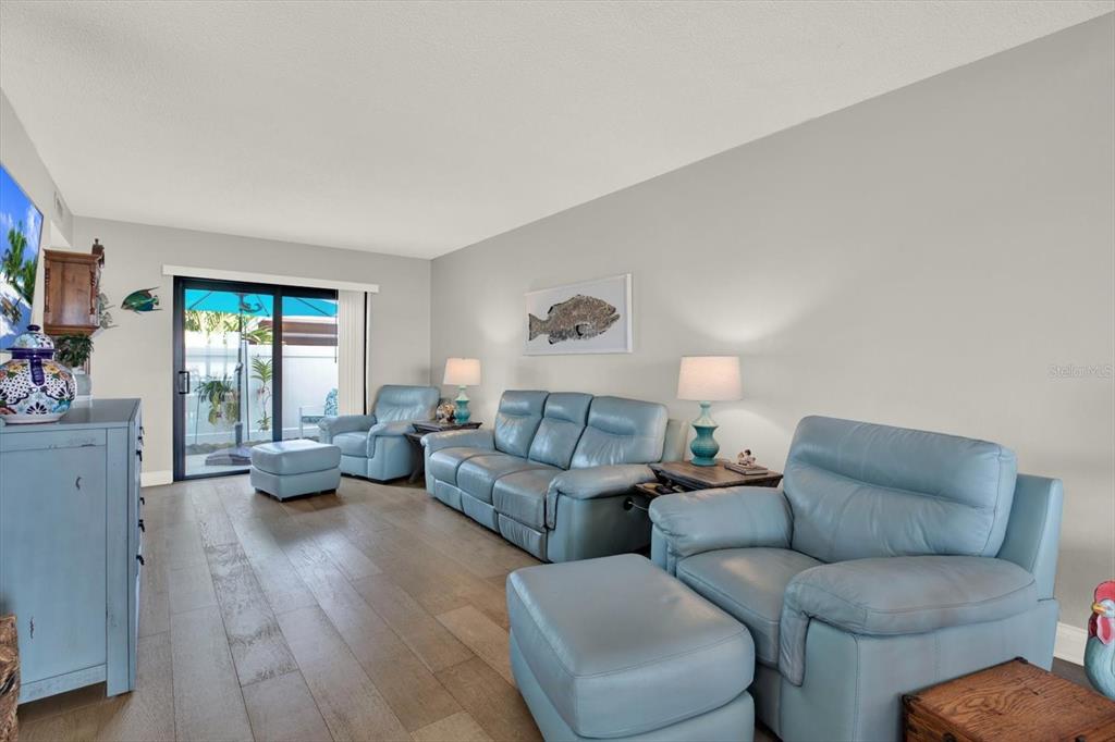 A living room features light blue leather furniture, wood-look flooring, and a sliding glass door — 9209 SEMINOLE BOULEVARD UNIT 14, SEMINOLE, FL