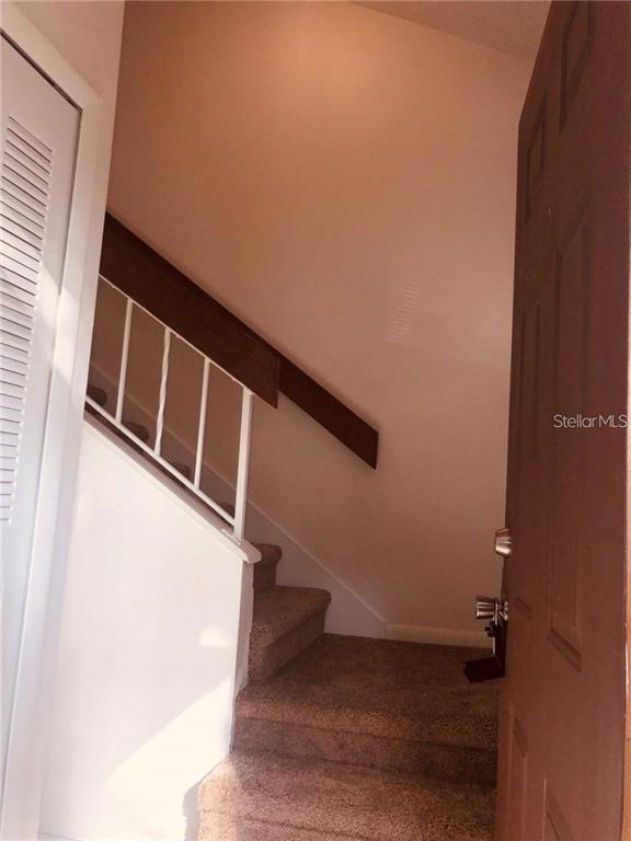 An interior view shows a carpeted staircase with a white railing leading to an upper level — 3036 S SEMORAN BOULEVARD UNIT M2, ORLANDO, FL