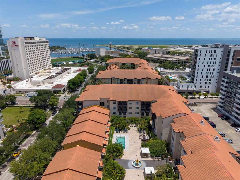 An aerial view shows a multi-story apartment complex with red tile roofs and a pool — 200 4TH AVENUE S UNIT 110, ST PETERSBURG, FL