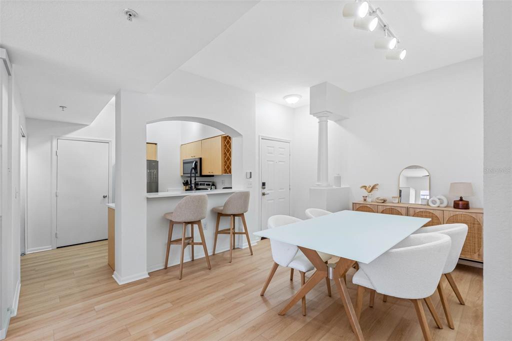 A dining area with a white table and chairs sits adjacent to an arched kitchen pass-through — 200 4TH AVENUE S UNIT 110, ST PETERSBURG, FL