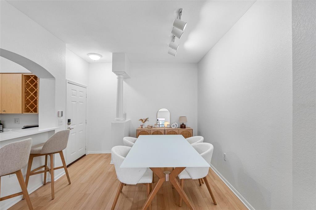 A dining area features a white table, four chairs, a wooden sideboard, and light flooring — 200 4TH AVENUE S UNIT 110, ST PETERSBURG, FL