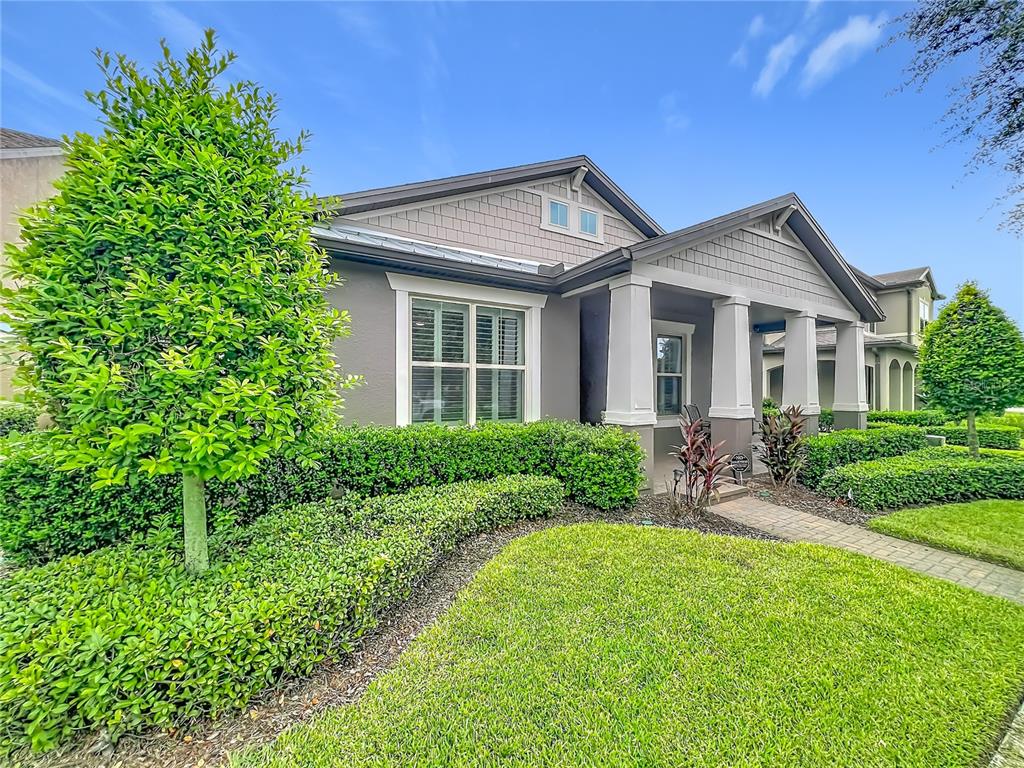 A single-story house with gray siding, a covered front porch, and manicured landscaping — 14048 LAKE ABBOTTS DRIVE, WINTER GARDEN, FL