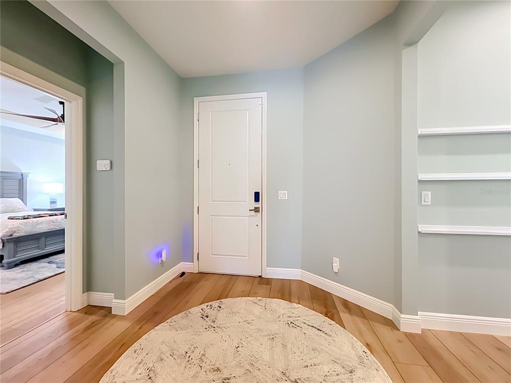 An entryway features light blue walls, hardwood flooring, a white door, and built-in shelving — 14048 LAKE ABBOTTS DRIVE, WINTER GARDEN, FL