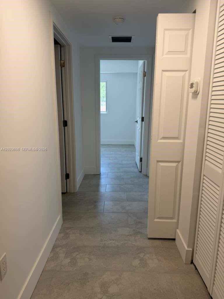 A hallway with light gray tile flooring leads to a doorway and an adjacent room — 147 Nw 59th St # 202, Miami FL 33127, MIAMI, FL