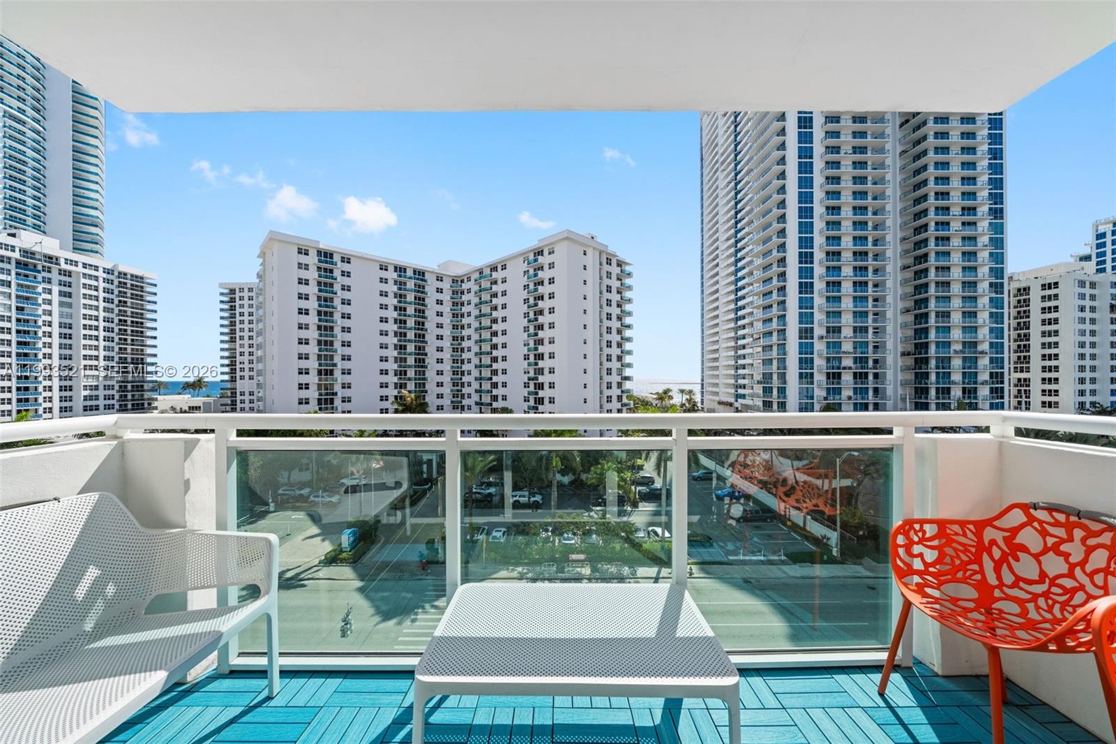 A living room features a white sectional sofa, a glass coffee table, and a wall-mounted television — 3000 S Ocean Dr # 606, Hollywood FL 33019, HOLLYWOOD, FL