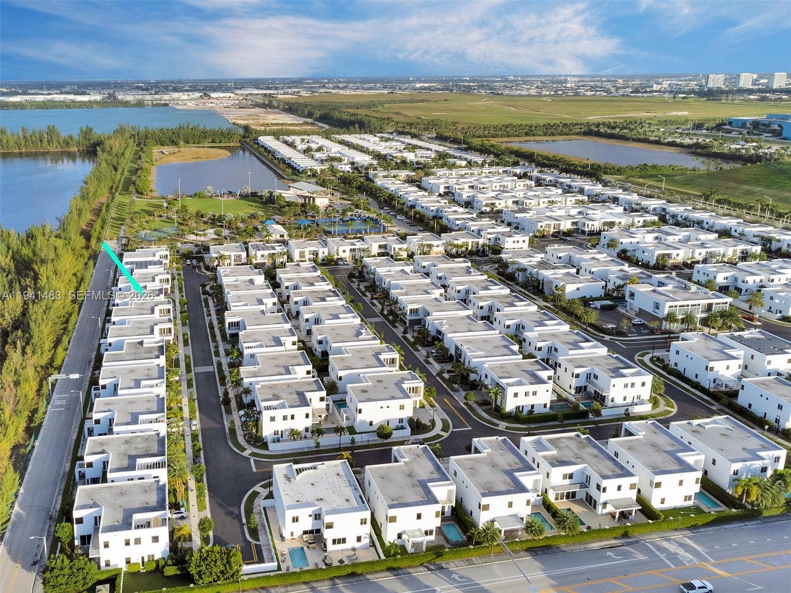 An aerial view shows a dense residential community of modern white houses with flat roofs — 10055 NW 77th St, Doral FL 33178, DORAL, FL