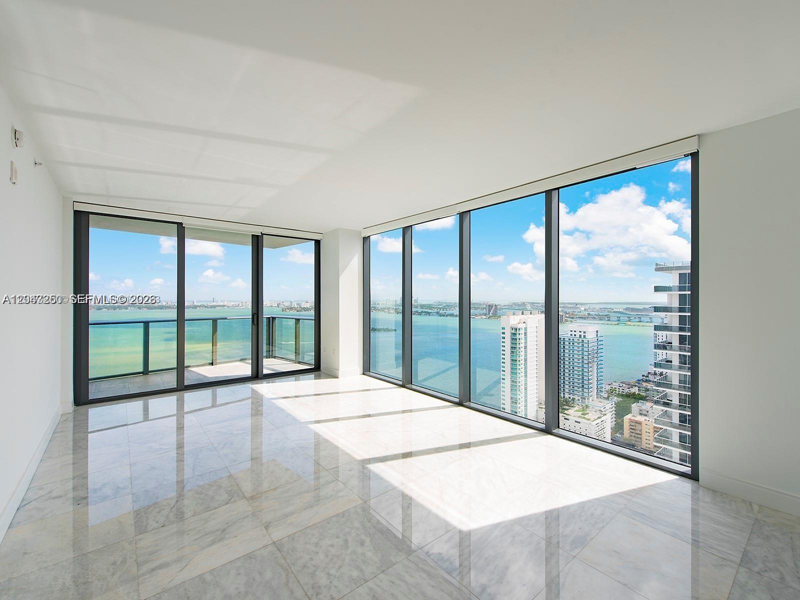 An empty room with marble floors and floor-to-ceiling windows overlooking a bay and city — 460 NE 28th St # 3608, Miami FL 33137, MIAMI, FL