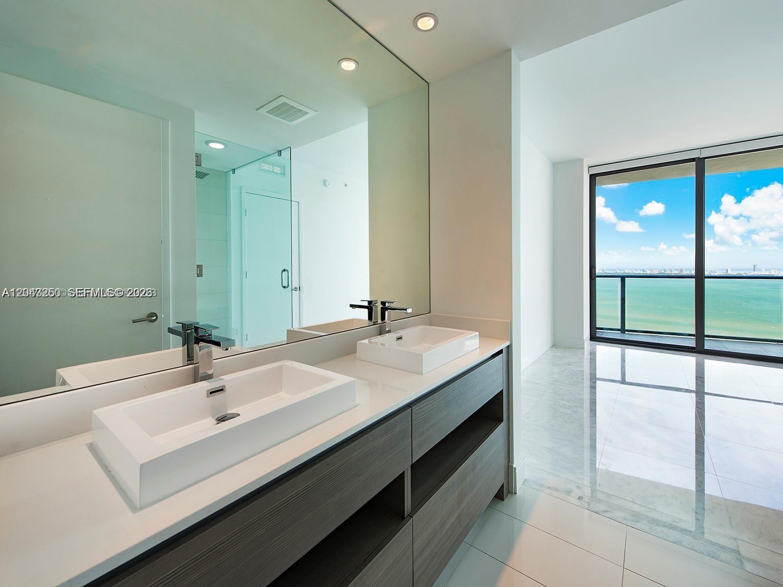 A modern bathroom features a double vanity with vessel sinks and a view of the ocean — 460 NE 28th St # 3608, Miami FL 33137, MIAMI, FL