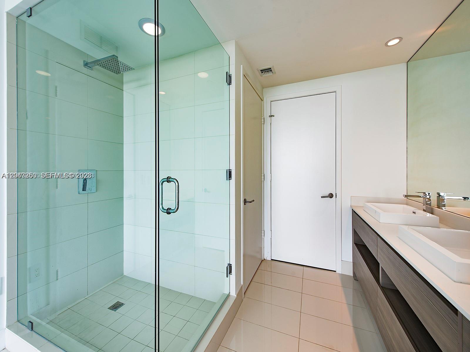 A modern bathroom features a glass-enclosed shower, double vanity, and white tiled walls — 460 NE 28th St # 3608, Miami FL 33137, MIAMI, FL