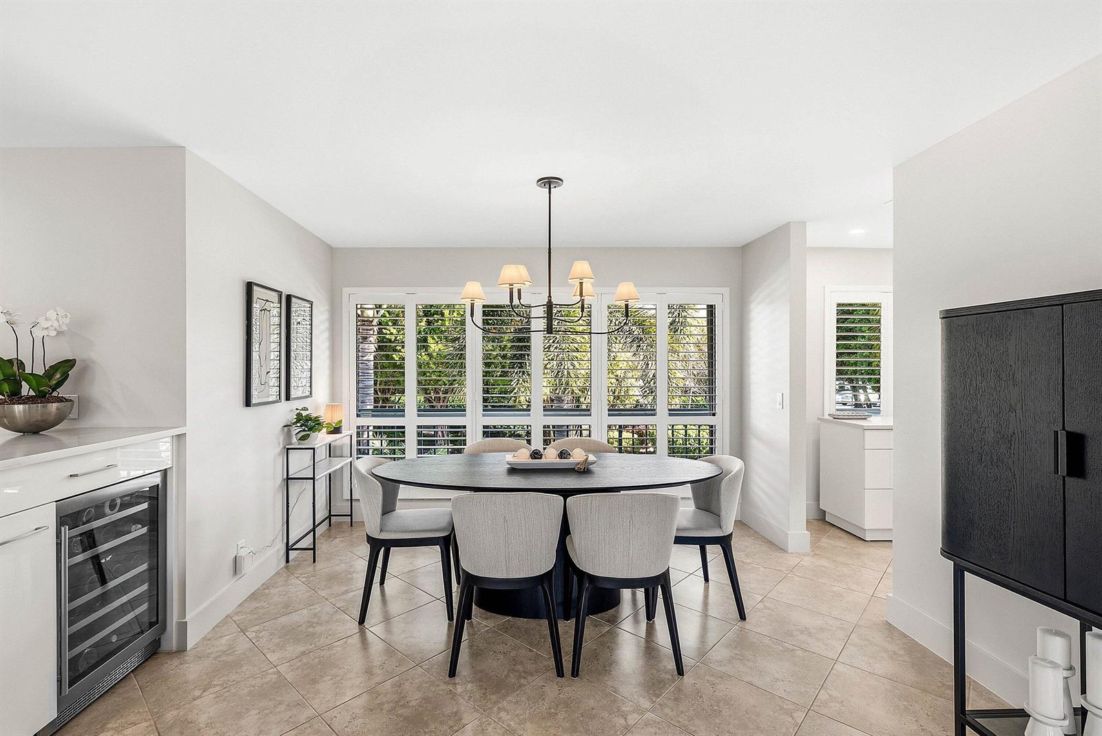 A dining room features a round black table, six upholstered chairs, and plantation shutters — 4114 B Quail Ridge Drive N, Boynton Beach FL 33436, BOYNTON BEACH, FL
