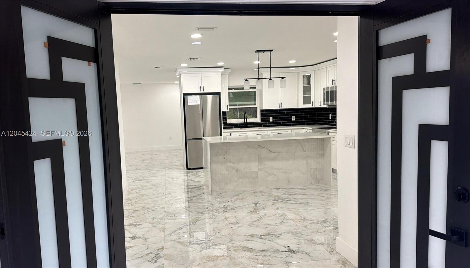 A modern kitchen with white cabinets, a marble island, and black tile backsplash — 3133 Washigton Road, Brandon FL 33594, BRANDON, FL