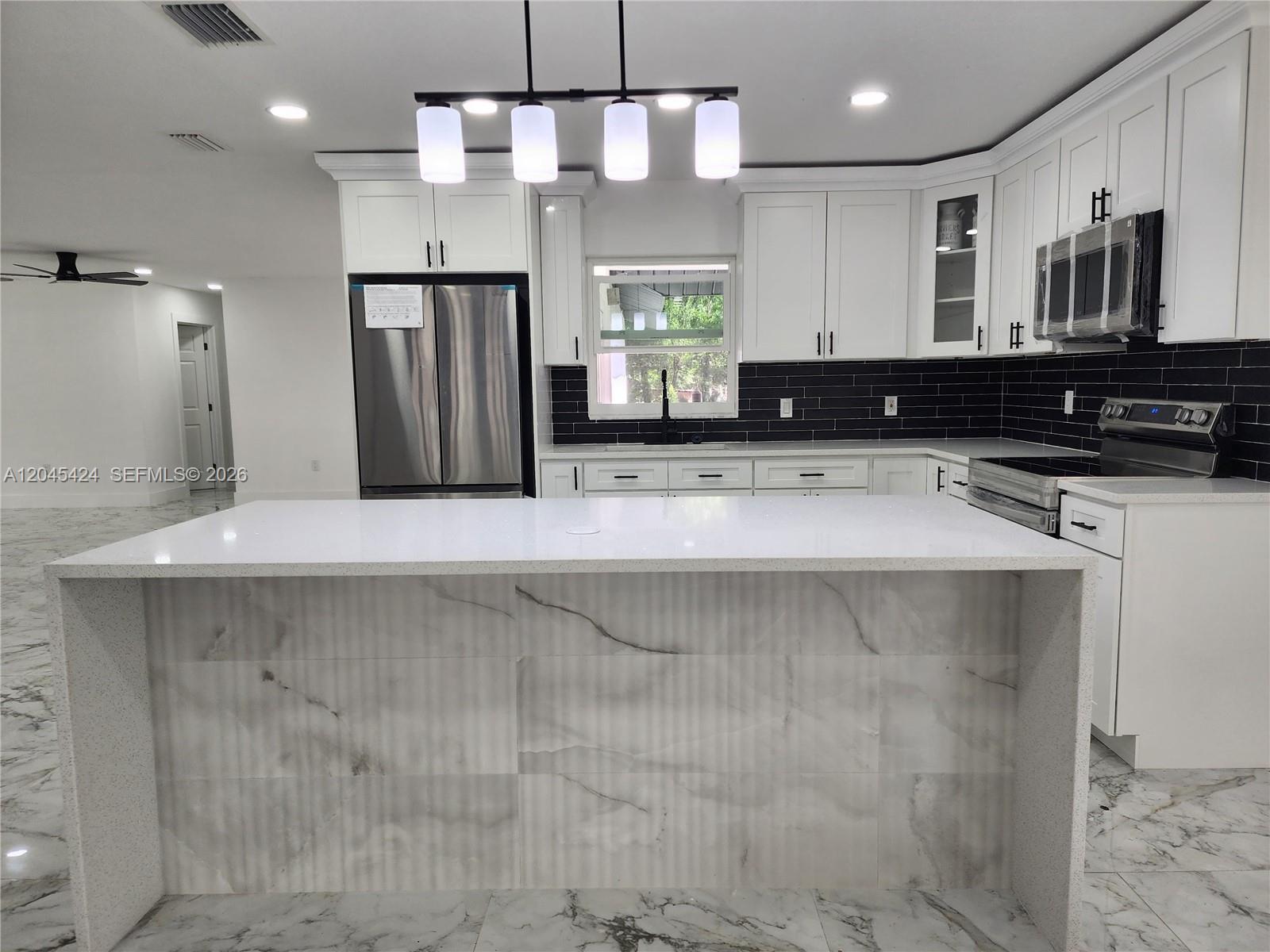 A modern kitchen features white cabinets, a marble-tiled island, and black subway tile backsplash — 3133 Washigton Road, Brandon FL 33594, BRANDON, FL