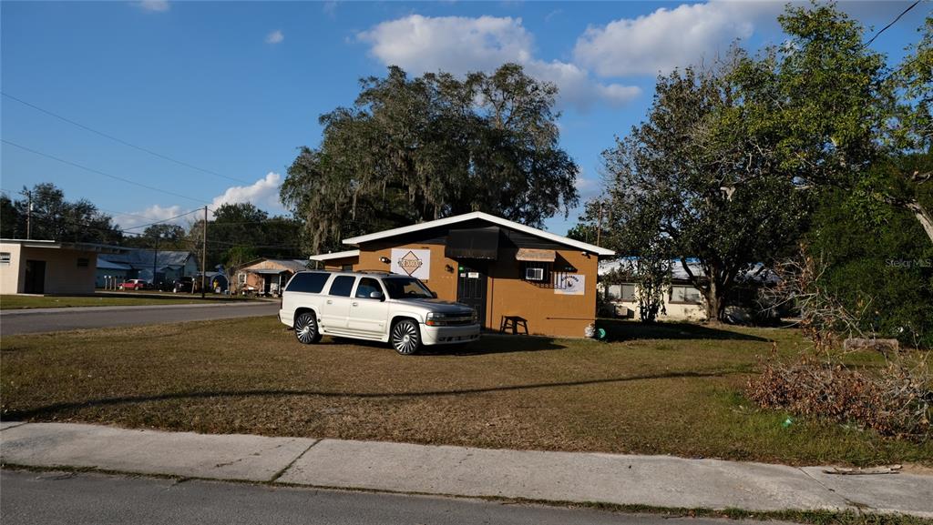 A white SUV is parked on the lawn in front of a tan commercial building — 34 4TH STREET SW, FORT MEADE, FL