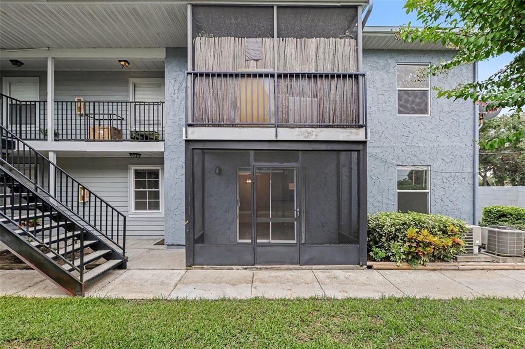 An exterior view of a two-story apartment building featuring screened-in patios and metal staircases — 3711 W IOWA AVE UNIT 115, TAMPA, FL