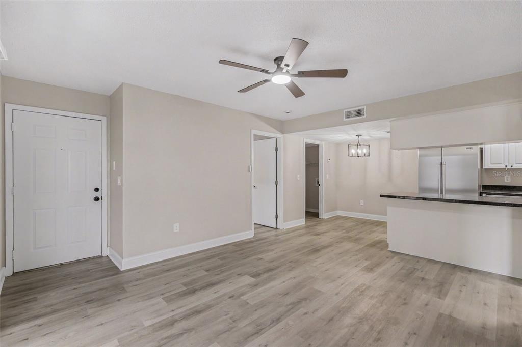 An open-concept living area features light wood-look flooring, a ceiling fan, and a kitchen counter — 3711 W IOWA AVE UNIT 115, TAMPA, FL