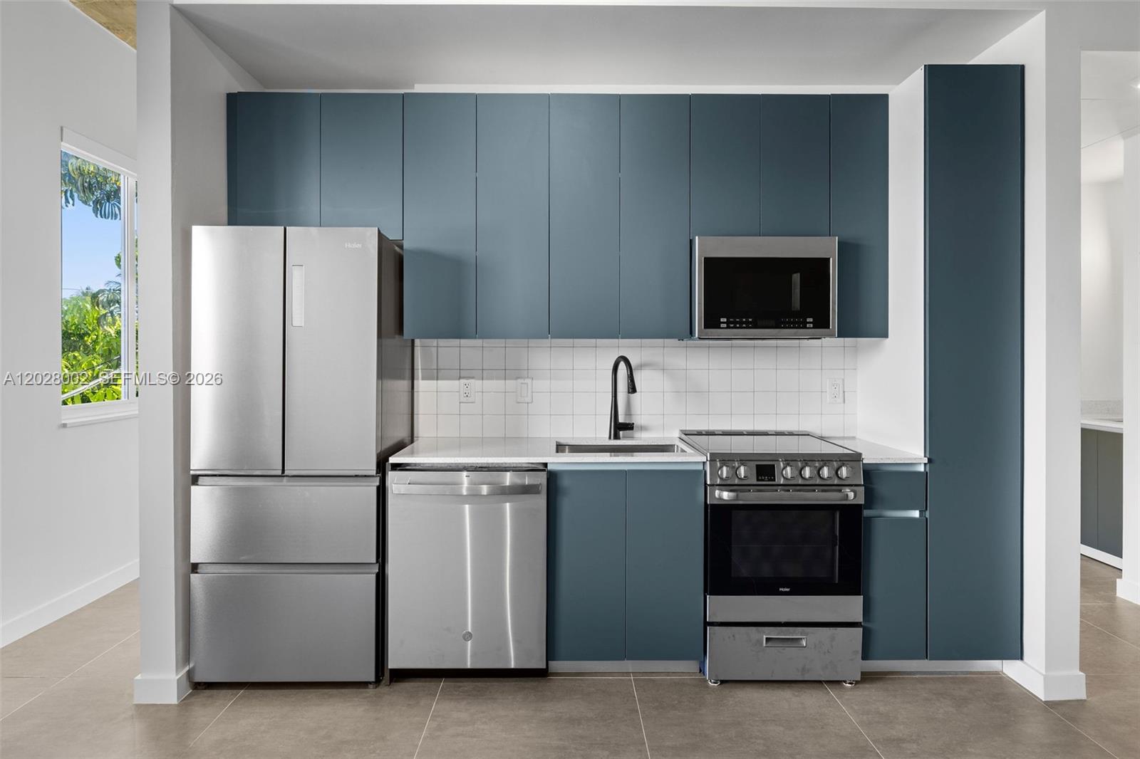 A modern kitchen features blue cabinets, stainless steel appliances, and a white tiled backsplash — 315 NW 32 ST # 306, Miami FL 33127, MIAMI, FL